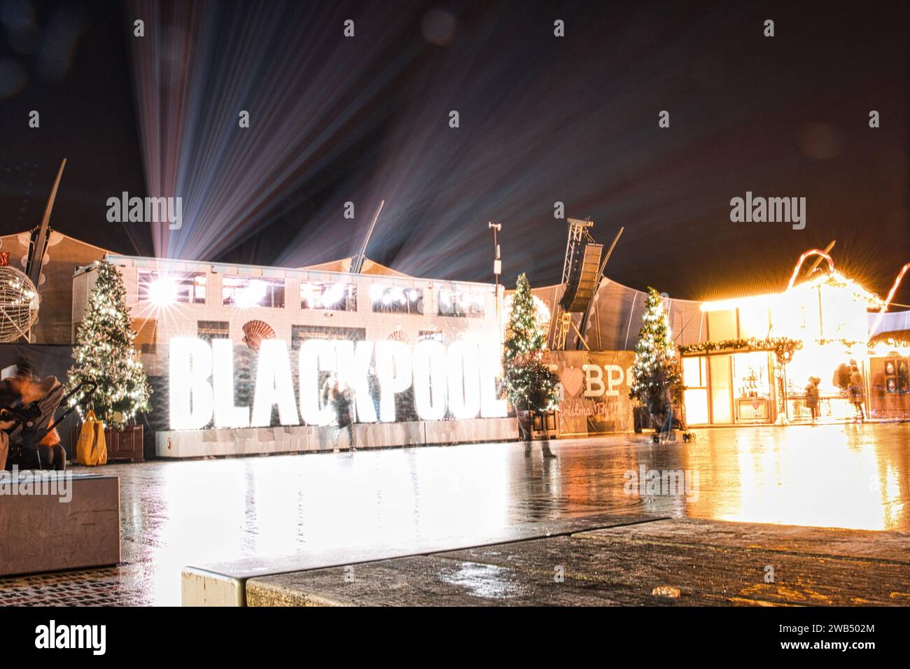 Nächtlicher Blick auf die Blackpool Illuminations mit hellen Lichtern und Reflexionen auf nassem Gehweg für eine festliche Atmosphäre. Stockfoto