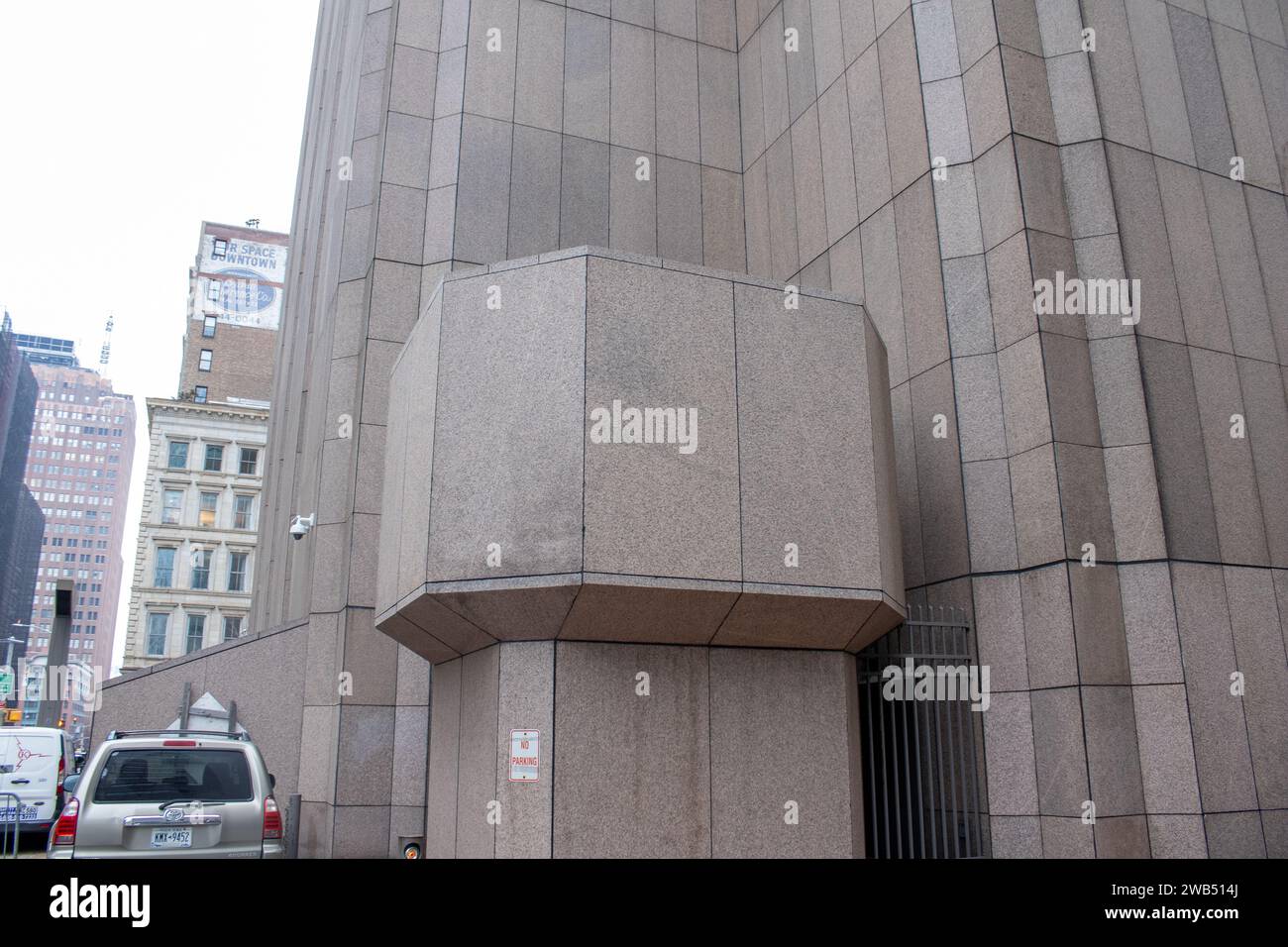 Ein junger erwachsener Mann steht auf einem Bürgersteig vor einem hohen Gebäude Stockfoto