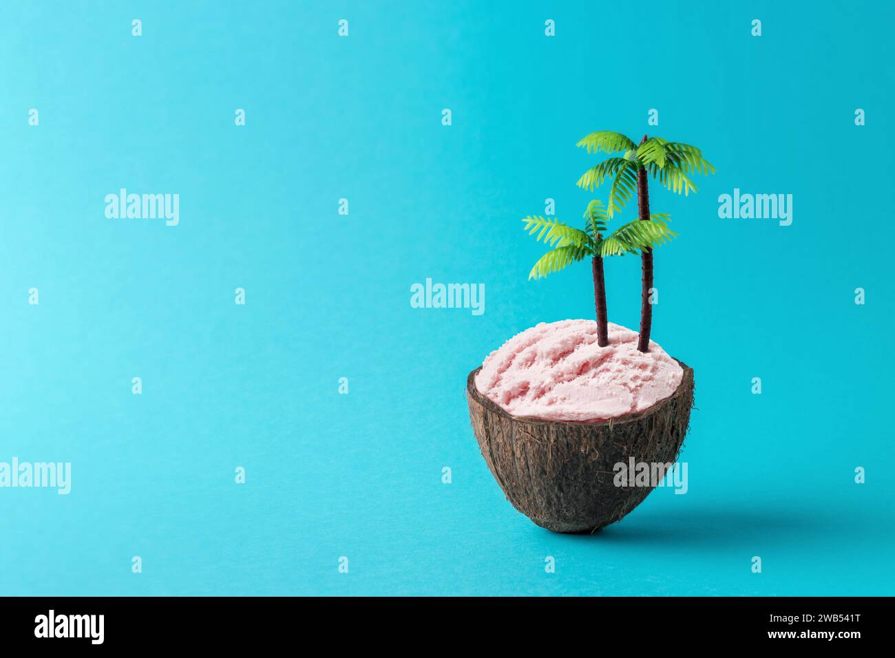 Tropische Kokosinsel mit Eis und Palmen auf blauem Hintergrund. Tropisches Strandkonzept. Kreative Idee für minimalen Sommer. Stockfoto