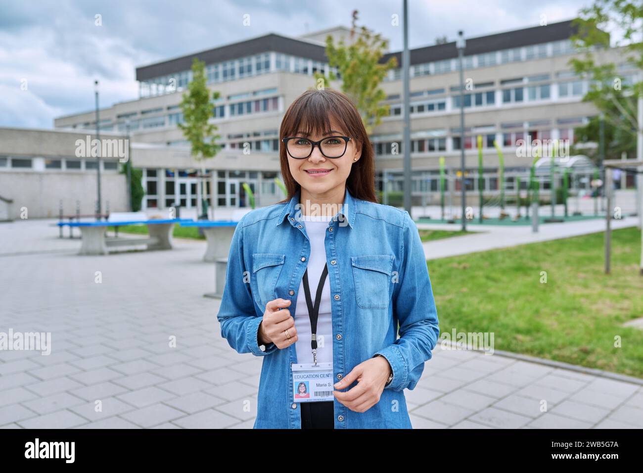 Selbstbewusste Lehrerin mittleren Alters in der Nähe des Schulgebäudes Stockfoto