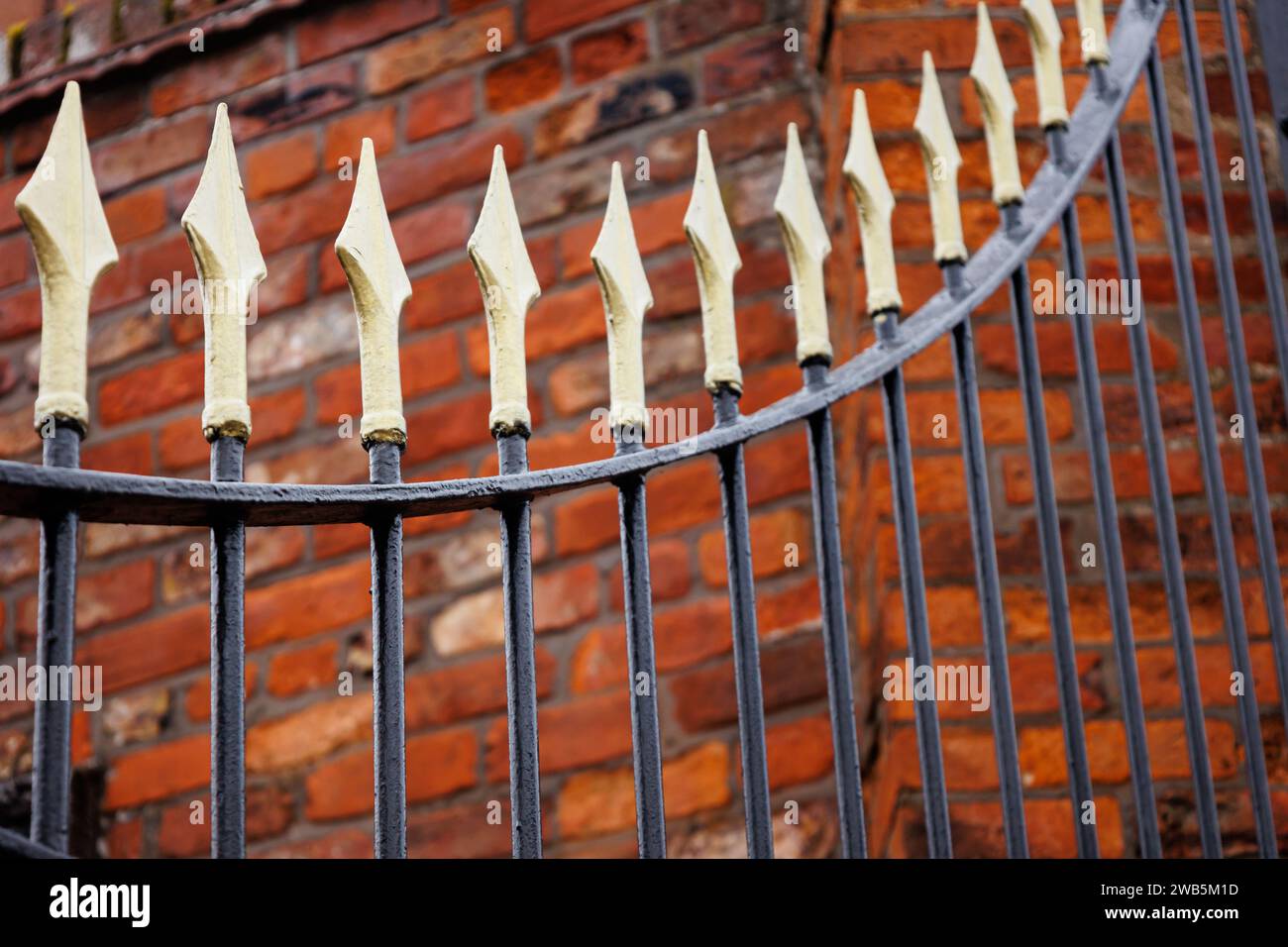 Goldenes und schwarzes Eisentor gegen alte Ziegelmauer, Hull, Großbritannien Stockfoto