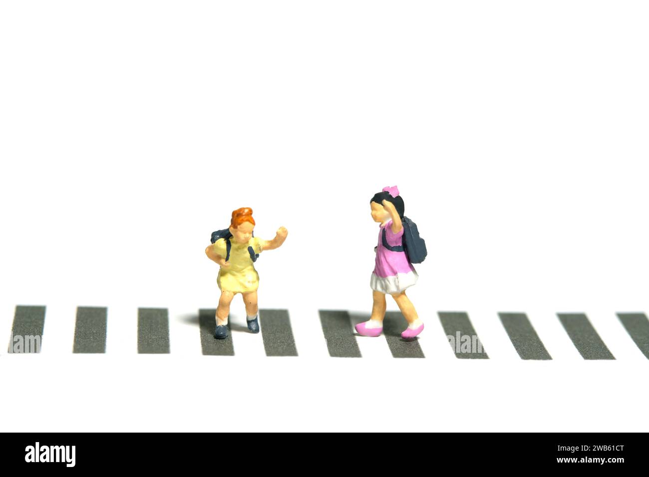 Miniatur-Kleinkinder spielten Fotografie. Zwei Kindergartenschüler, die über die Zebraüberquerung laufen. Isoliert auf weißem Hintergrund. Bild Foto Stockfoto