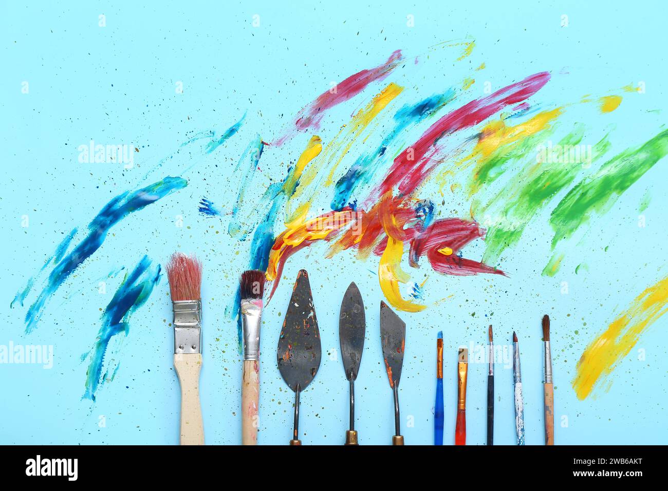 Künstlerpinsel, Palettenmesser und Farben auf blauem Hintergrund Stockfoto
