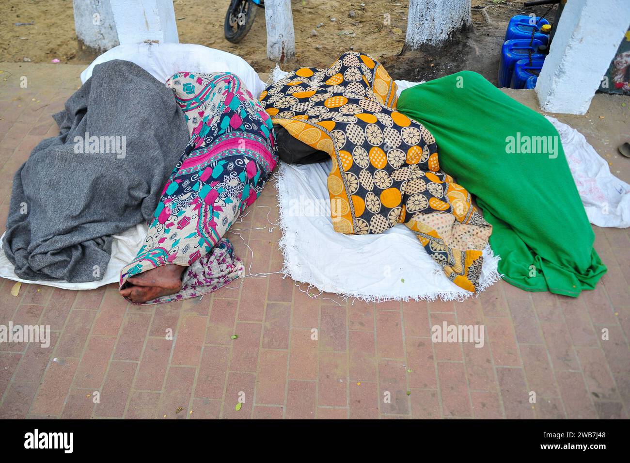 Obdachlose Menschen bedecken ihre Körper von Kopf bis Fuß mit allem, was sie schaffen können, schlafen draußen in der zitternden Kälte nahe der Regierung Alia Madrasa in Sylhet-Stadt Chowhatta. Laut der Bevölkerungszählung von 2011 durch das Bangladesch Bureau of Statistics (BBS) betrug die Sylhet-Bevölkerung 479.837. Die heutige Bevölkerungswachstumsrate in Sylhet beträgt 2,5 % pro Jahr. Angesichts der Tatsache, dass täglich 10 % der schwimmenden Bevölkerung in die Stadt kommen, wird die heutige (2020) Bevölkerung auf etwa 659 176 geschätzt. Sylhet, Bangladesch. Stockfoto