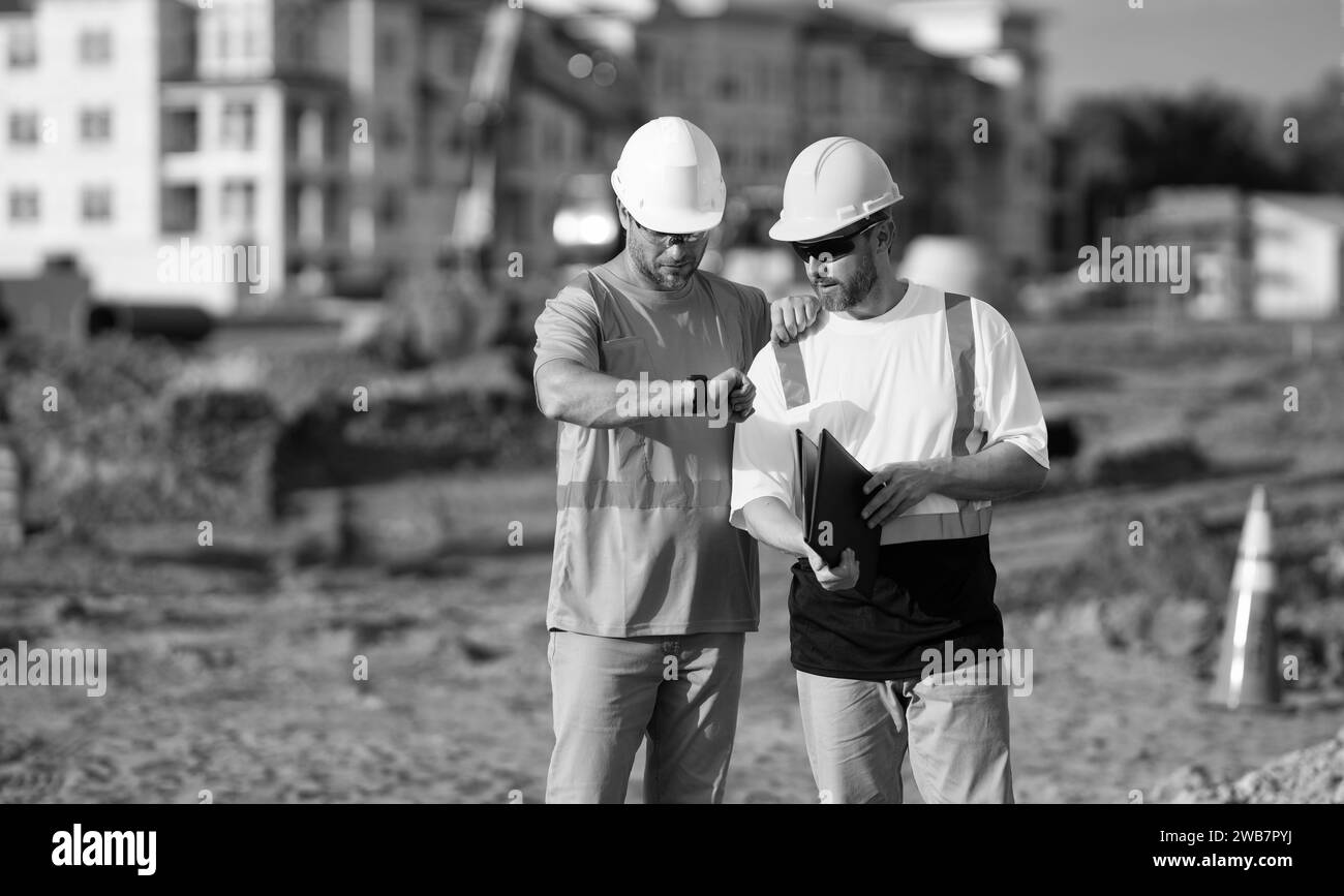 Bauvorarbeiter und Bauingenieur bei der Arbeitszeitüberprüfung Stockfoto