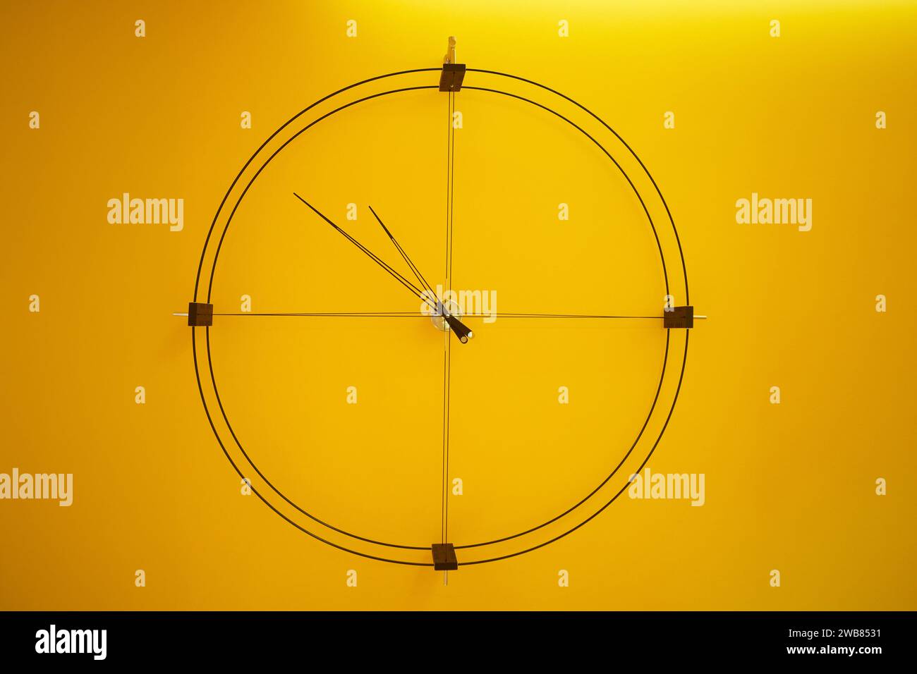 Moderne, minimalistische Wanduhr im Loft-Stil an gelber Wand. Stockfoto