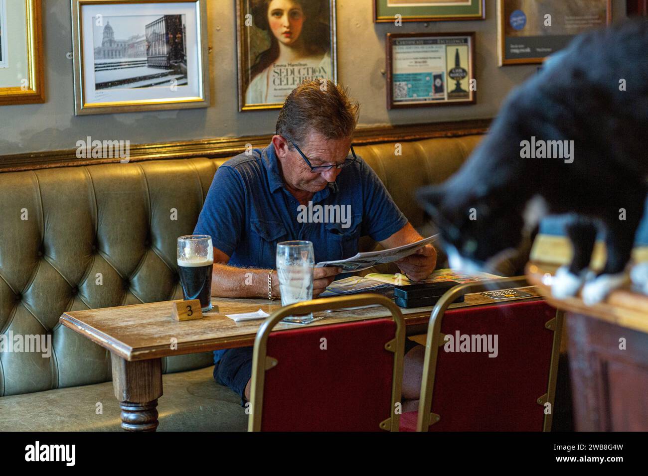 Ein Mann trinkt Bier und liest Zeitung im Pub Stockfoto