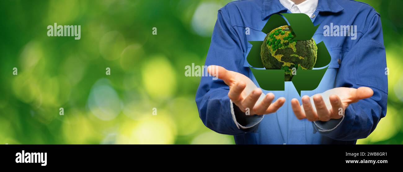Ein Ingenieur hält einen grünen Planeten Erde mit Recycling-Symbol. Stockfoto