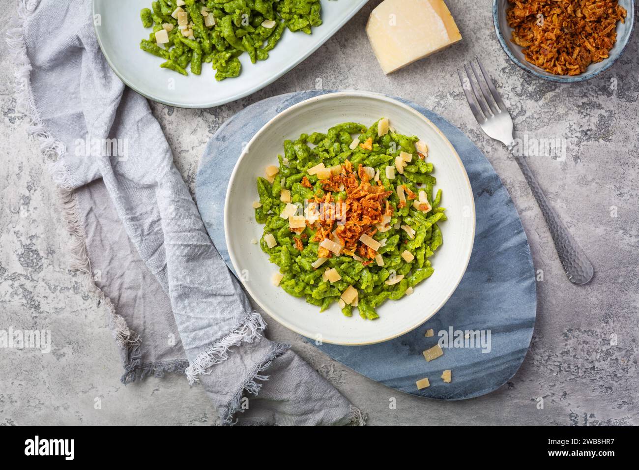 Spinatspätzle mit Parmesan und gerösteten Zwiebeln - Deutsche Eiernudeln Stockfoto