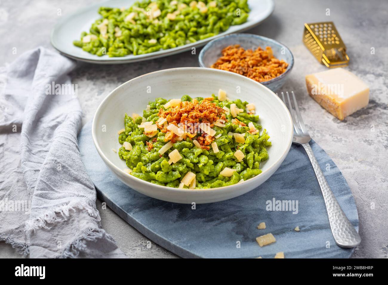 Spinatspätzle mit Parmesan und gerösteten Zwiebeln - Deutsche Eiernudeln Stockfoto