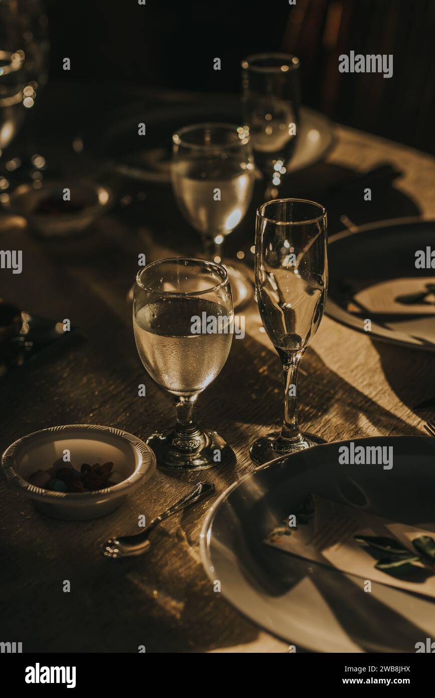 Ein weißer Esstisch ist mit Gläsern und Tellern besetzt. Stockfoto