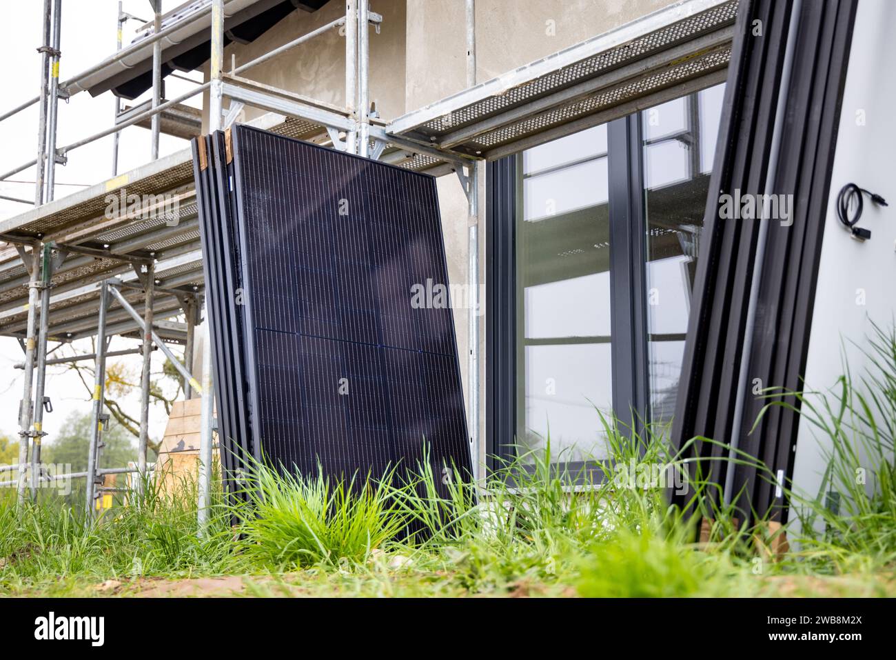 Solarpaneele warten auf Installation neben Gerüsten auf einer Baustelle Stockfoto