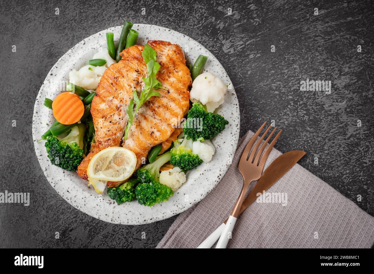 Lachssteak mit Gemüse Blumenkohl, Brokkoli, Karotten und grünen Bohnen. Salat aus Rucola und Gemüse mit Lachs. Draufsicht, flach Stockfoto