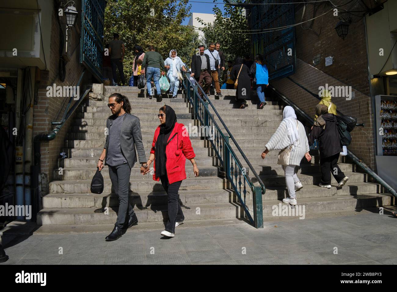 Klug gekleidete junge Mann und Frau gehen gemeinsam Hände haltend im historischen Zentrum von Teheran, Iran. Stockfoto