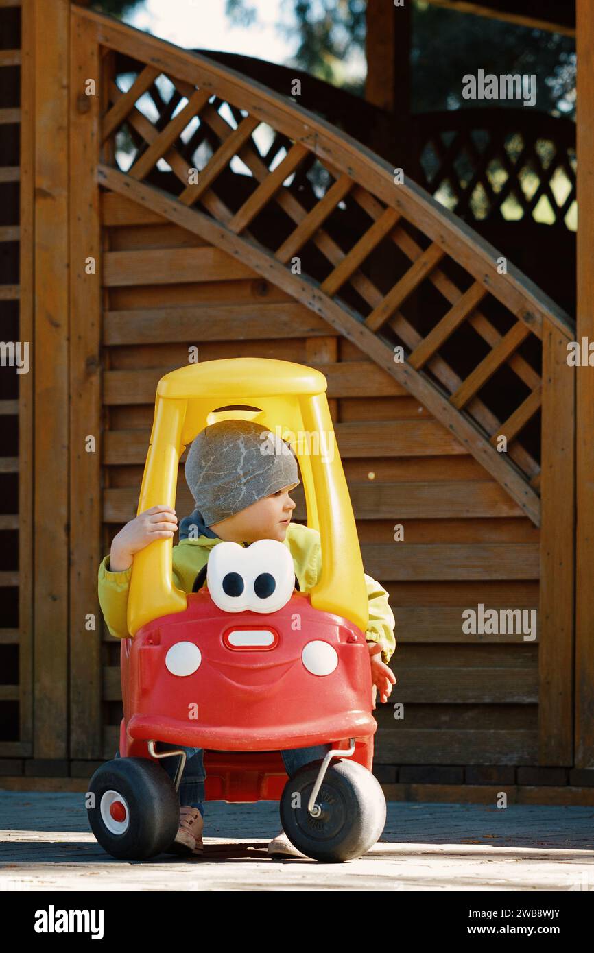 Porträt des niedlichen kleinen Kaukasain-Kleinkindes Spaß beim Reiten eines Spielzeugautos im Stadtpark am Frühlingstag. Stockfoto