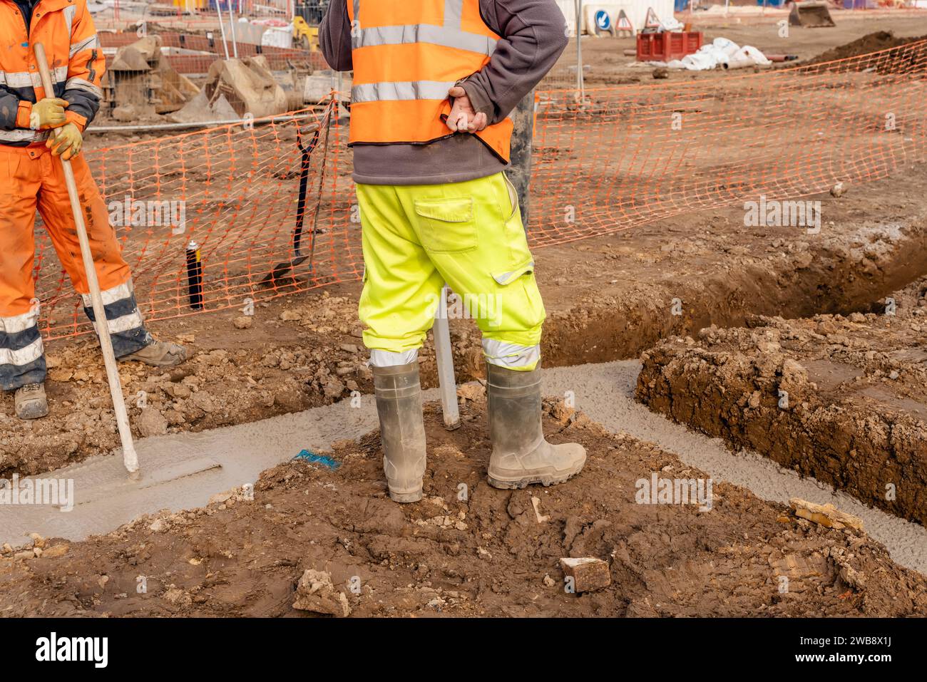 Mobile Betonpumpe auf der Baustelle gebrauchte Nebenbauer, die das Hausfundament mit nassem Transportbeton gießen Stockfoto