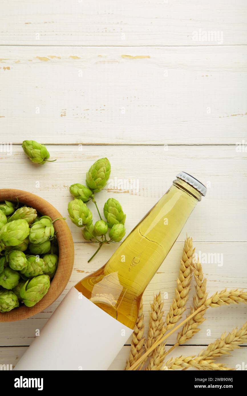 Bierflasche mit Hopfen und Weizen auf weißem Hintergrund, Nahaufnahme. Draufsicht Stockfoto