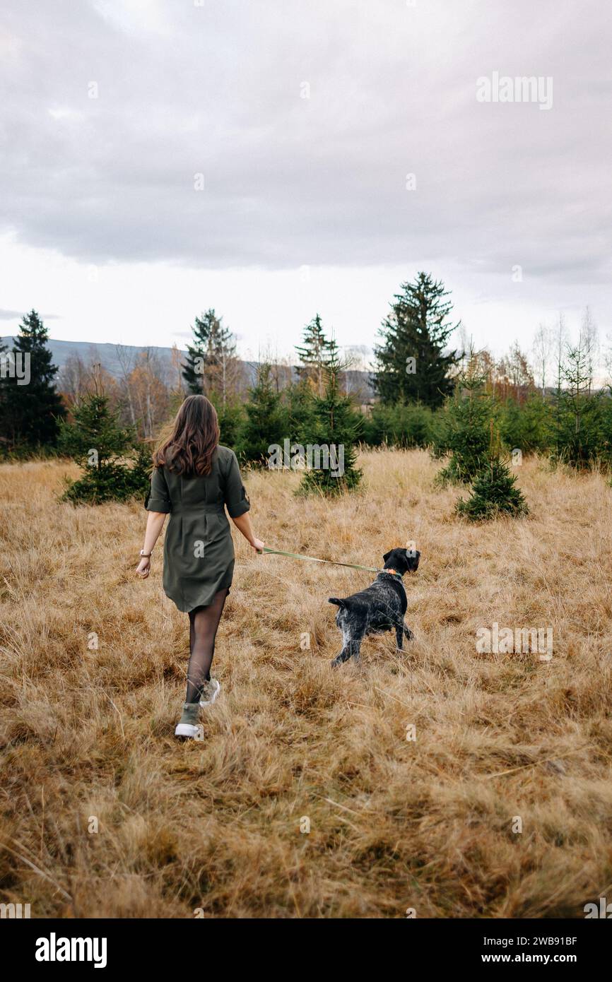 Junge Dame, die mit ihrem Hund in der Natur läuft Stockfoto