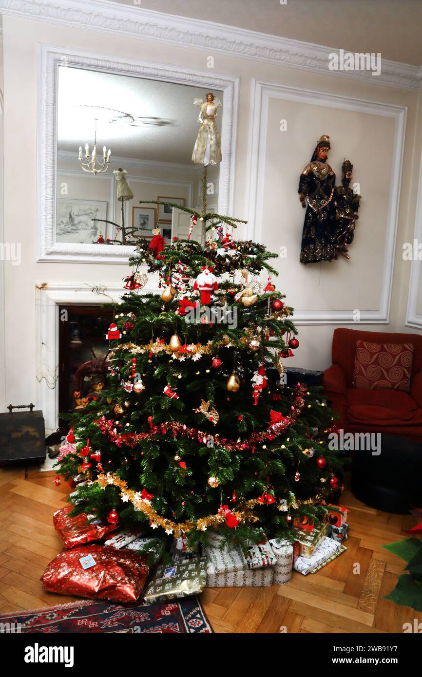 Geschenkverpackungen rund um den dekorierten echten Weihnachtsbaum im Wohnzimmer Surrey England Stockfoto