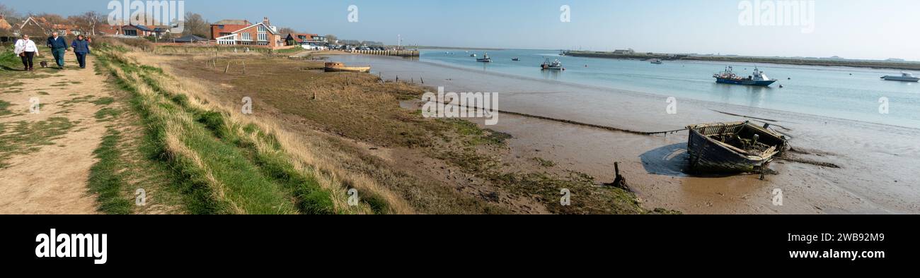 Spaziergänger entlang der Küste von Orford Ness Suffolk England mit Gezeiten und festgefahrenen Booten Stockfoto
