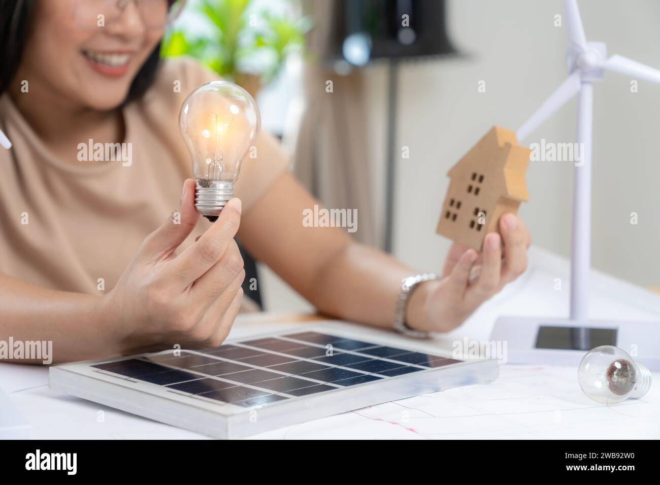 Junge asiatische Frau mit Sonnenkollektor und Glühbirne, Solarenergiekonzept. Stockfoto