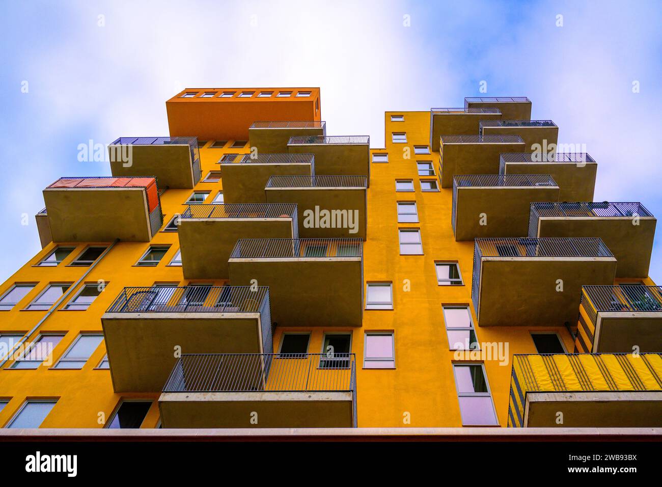 Ein modernes Apartmentgebäude mit einer hellgelben Fassade, die eine lebendige visuelle Wirkung erzeugt Stockfoto