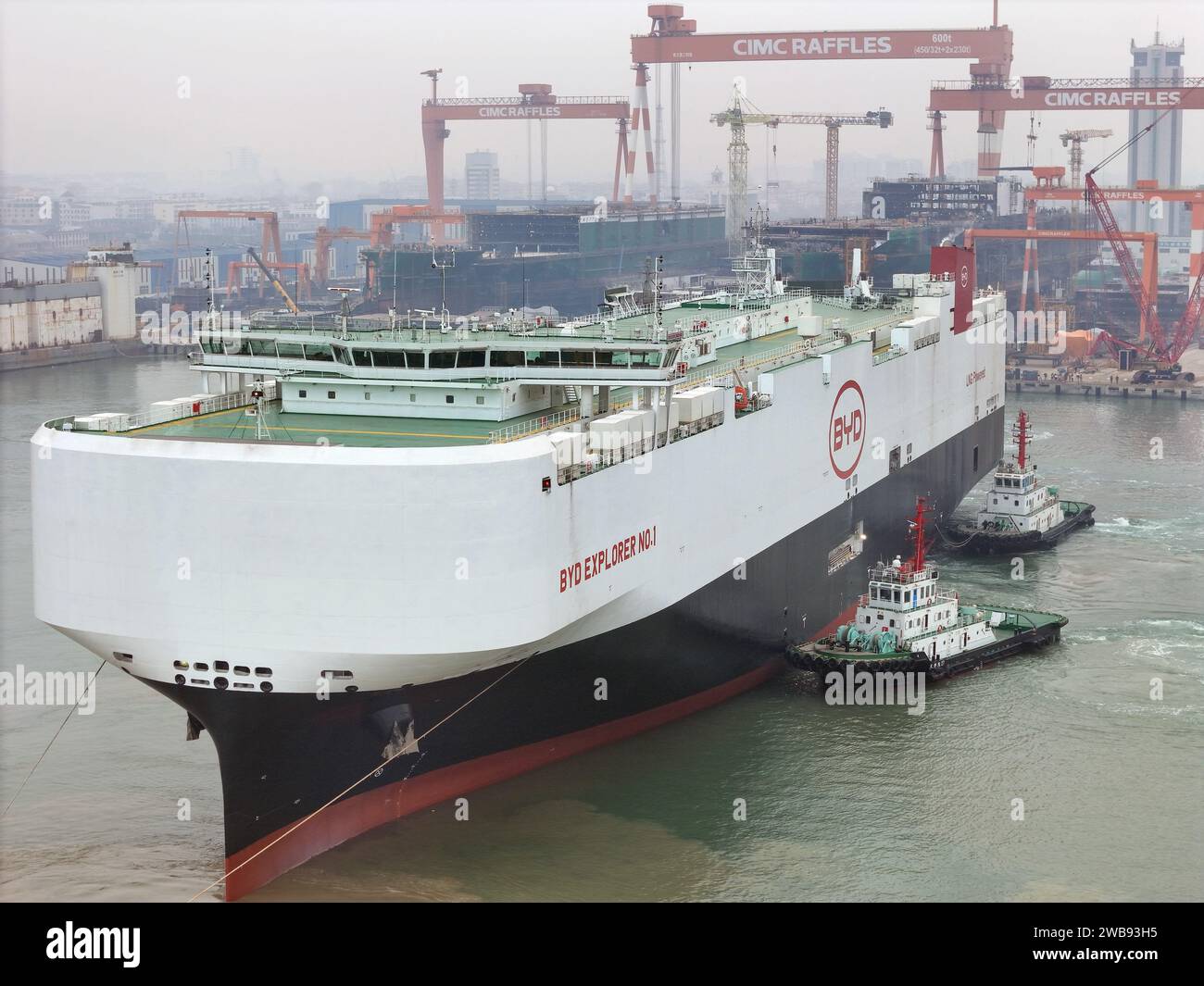 YANTAI, CHINA - 9. JANUAR 2024 - der große Autoträger BYD Explorer 1 wird von einem Schlepper auf der CIMC Raffles' Shandong Longkou Baubasis in unterstützt Stockfoto