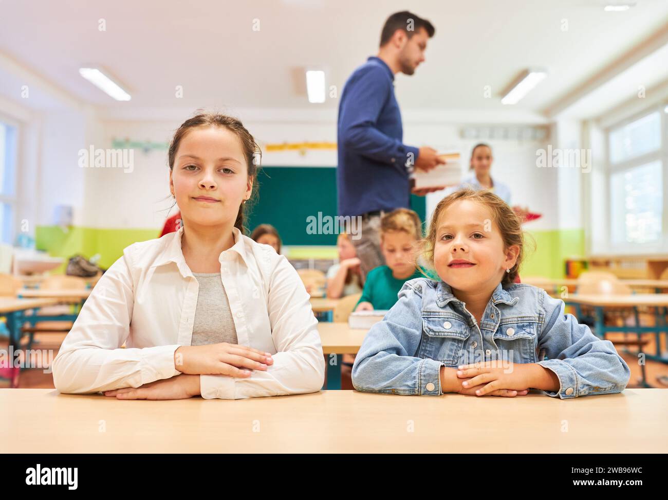 Porträt von Grundschulmädchen, die im Klassenzimmer zusammen auf der Bank sitzen Stockfoto