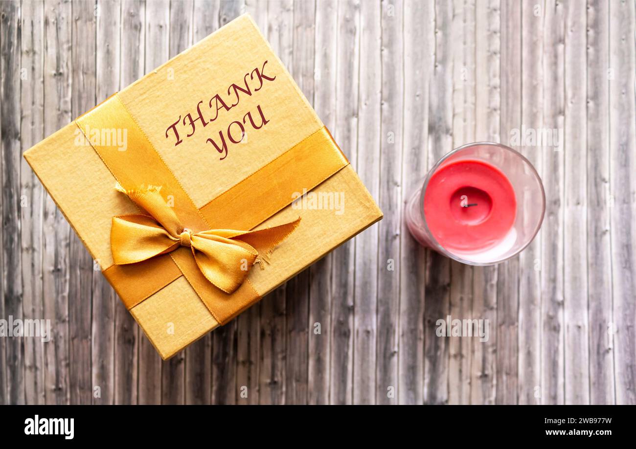 Danksagung auf Geschenkbox und hölzernem Hintergrund mit Kerze Stockfoto