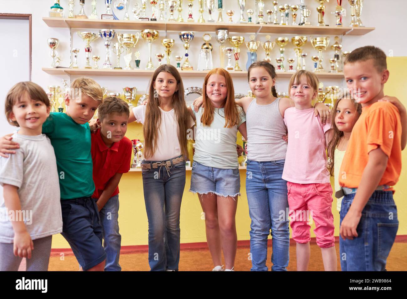 Porträt von Grundschulkindern mit Sporttrophäen auf dem Ausstellungsregal Stockfoto