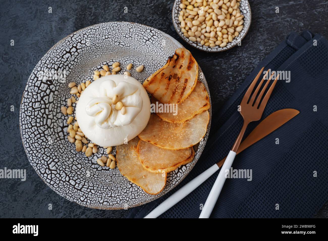 burrata wird mit gerösteten karamelisierten Birnen- und Pinienkernen serviert. Draufsicht, flach. Stockfoto