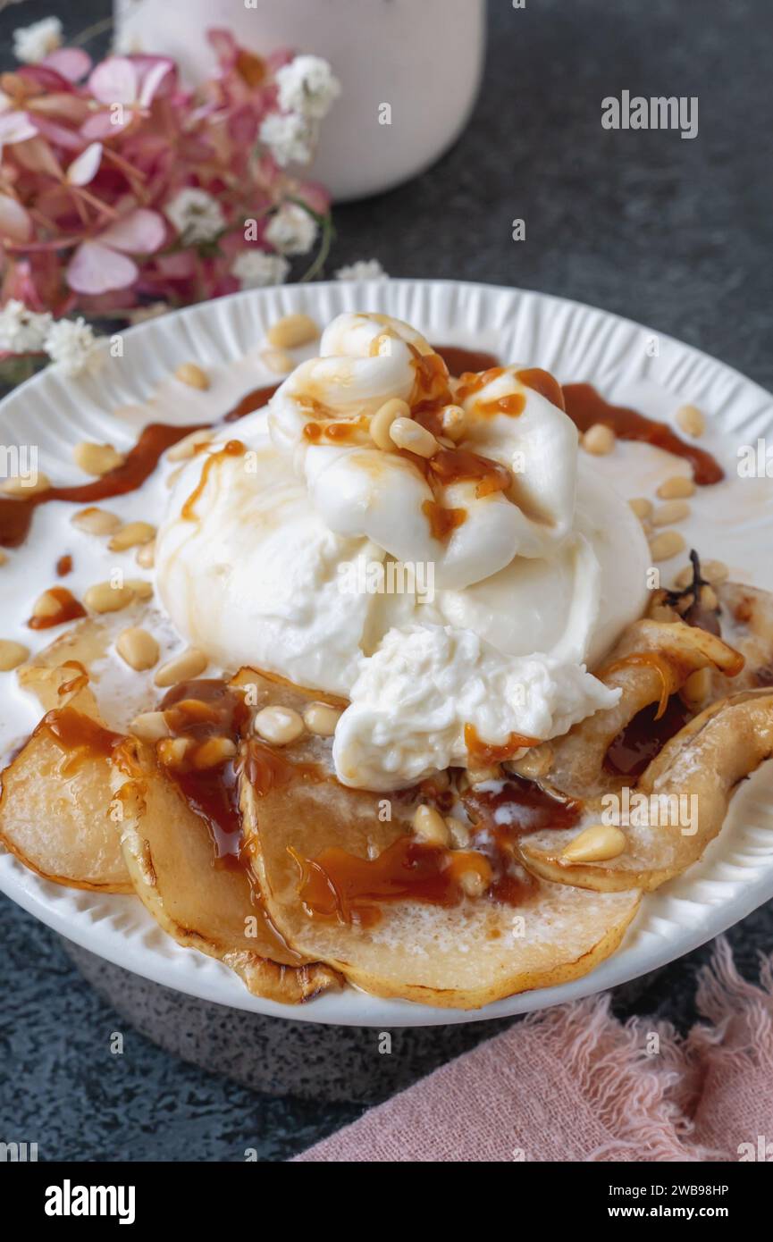 burrata wird mit gerösteten karamelisierten Birnen- und Pinienkernen serviert. Nahaufnahme. Stockfoto