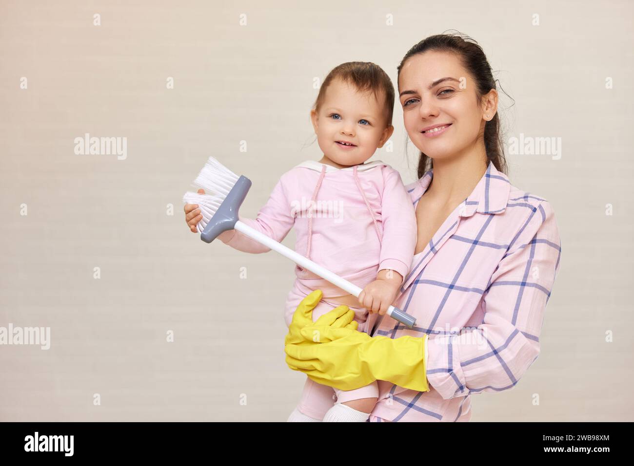 Lächelnde Mutter Hausfrau hält süßes Baby und macht Hausarbeit zu Hause, glückliche Familie, Kopierraum Stockfoto