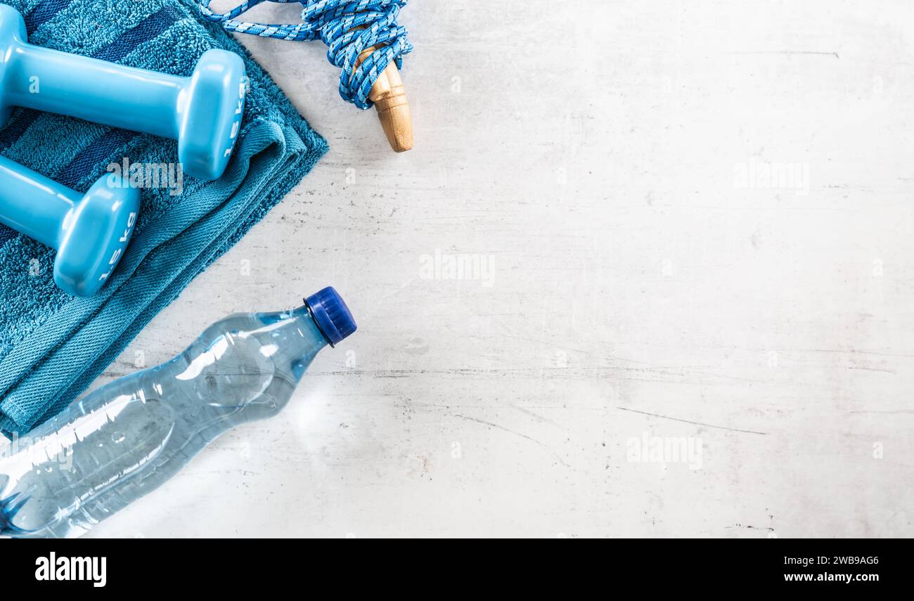 Set aus Sportausrüstung, Kurzhanteln, Sprungseil, Handtuch und Wasserflasche. Sport und gesundes Lifestyle-Konzept. Stockfoto