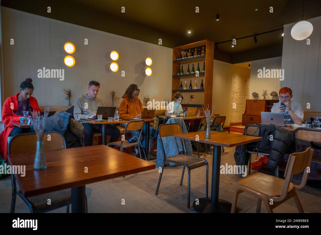 Junge Berufstätige, die an Laptop-Computern in der Cafe Bar London arbeiten, Januar 2024 Stockfoto