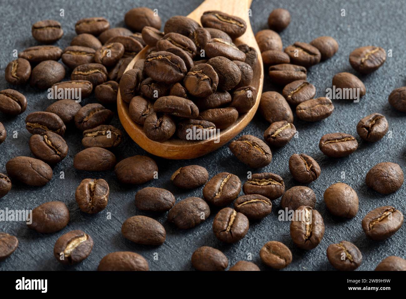 Ein Löffel voller gerösteter Kaffeebohnen auf schwarzem Hintergrund Stockfoto