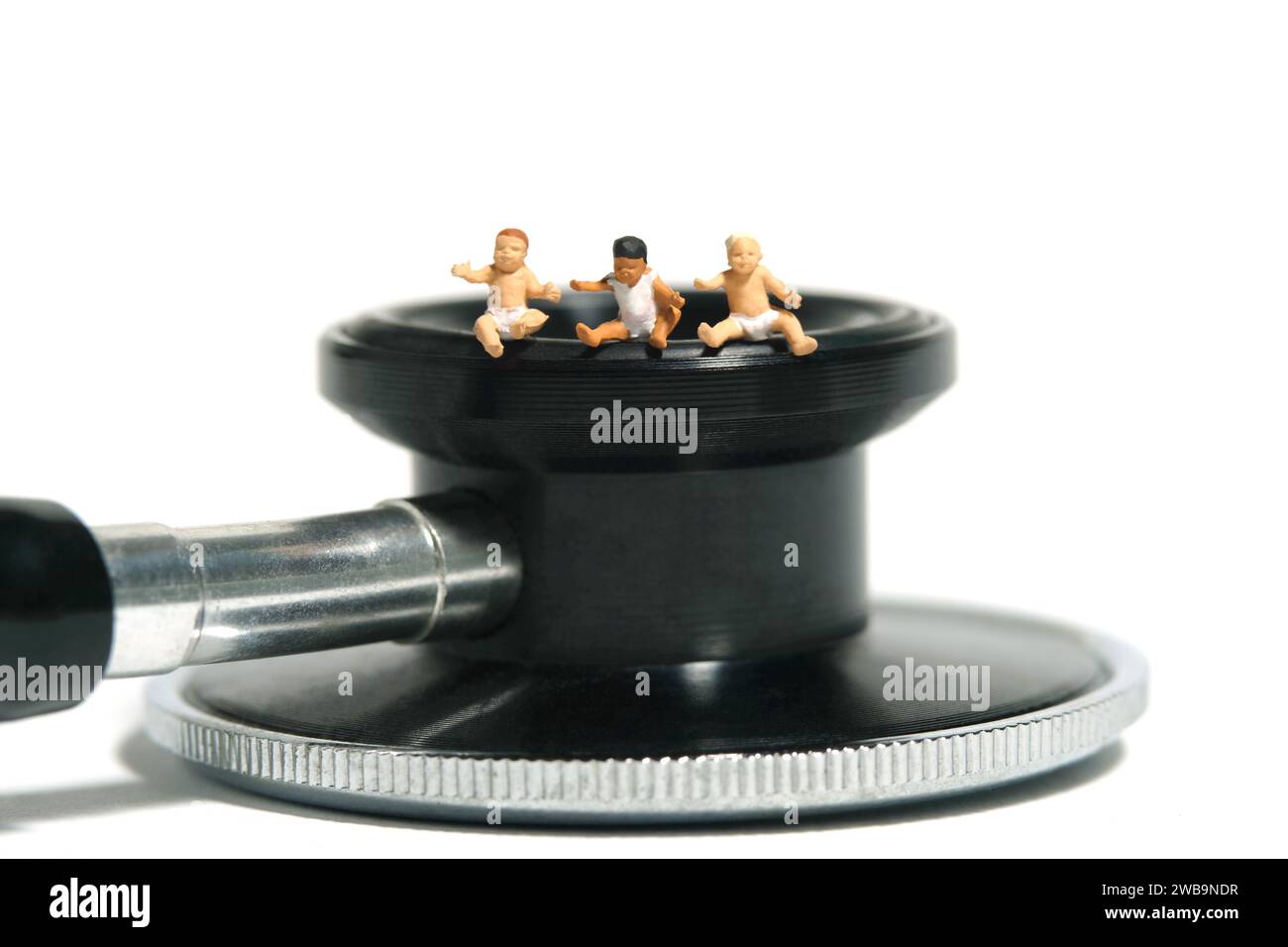 Miniatur-Kleinkinder-Spielfiguren-Fotografie. Gruppe von Kleinkindern, die über dem Stethoskop sitzen. Isoliert auf weißem Hintergrund. Bild Foto Stockfoto
