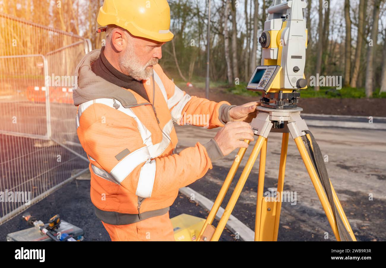 Der Bauingenieur stellt sein Gerät während der Bauarbeiten ein. Bauherr, der Tachymeter für die Gesamtpositionierung auf der Baustelle für die neue Straße setti installiert Stockfoto