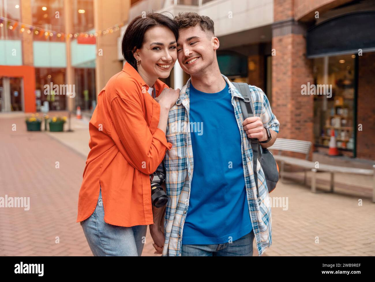 Zwei Freunde, ein Paar, das eine Kamera benutzt, Selfie gegen eine rote Telefonbox macht, Fotos auf der Kamera ansieht, Spaß in der Stadt England hat Stockfoto