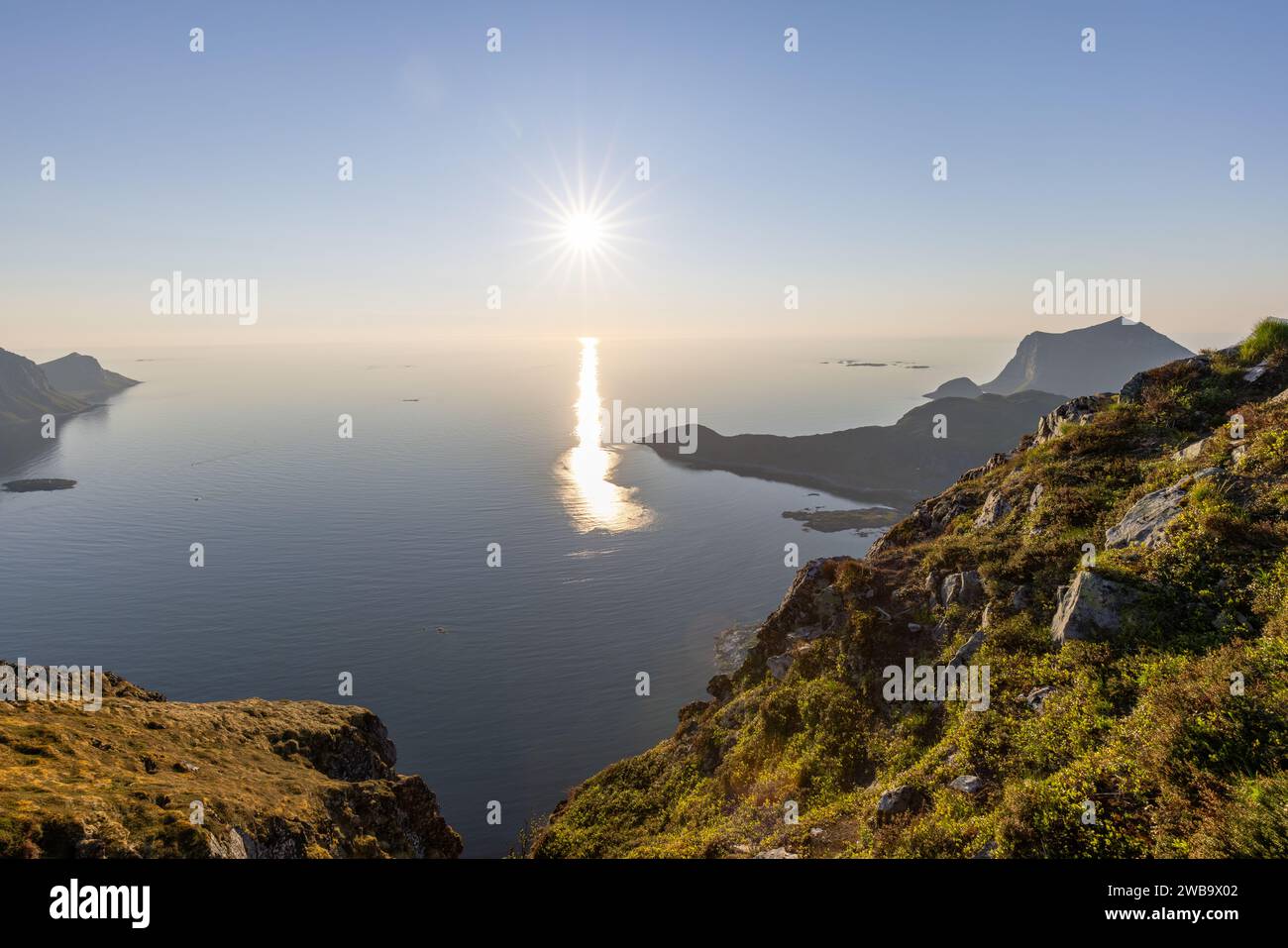 Eine schillernde Mitternachtssonne schwebt über Offersoykammen, deren Licht von den Nappstraumen reflektiert und die Gipfel der Lofoten umrahmt Stockfoto