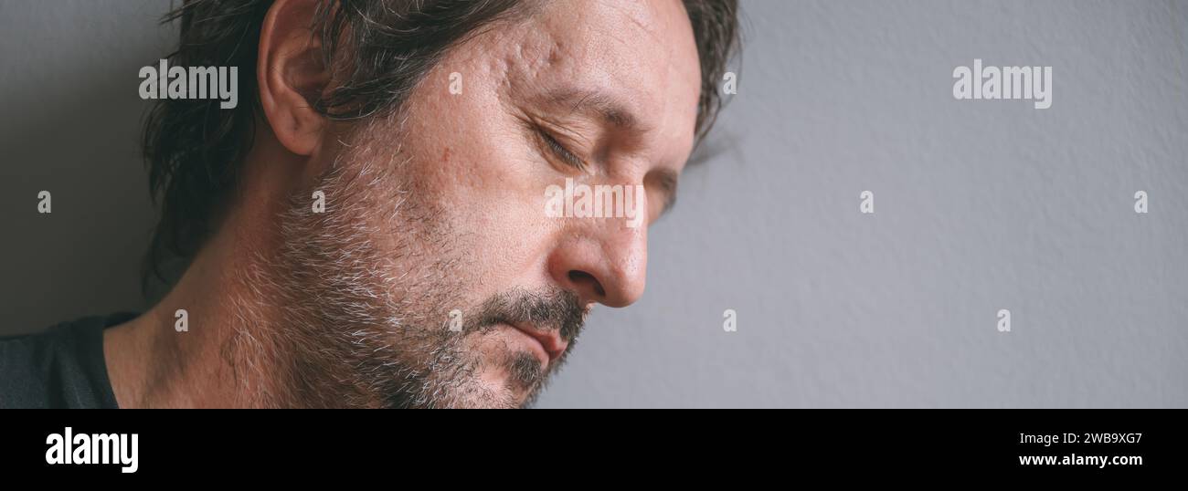 Müder, schläfriger Mann, der seinen Kopf gegen die Wand lehnt, mit geschlossenen Augen, selektiver Fokus Stockfoto