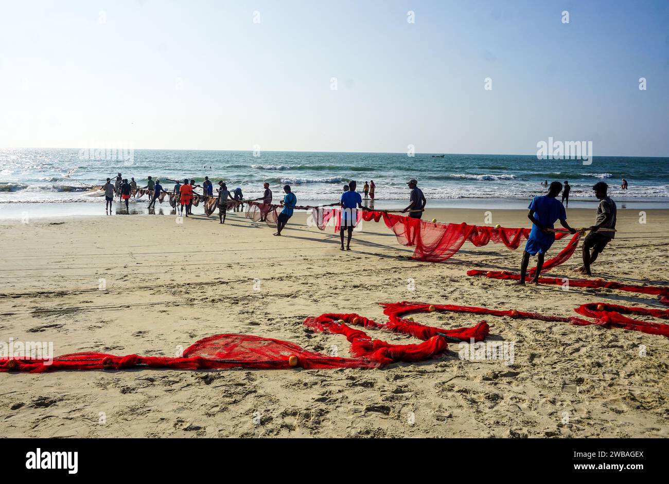 Fischer am Strand von Benaulim im indischen Goa ziehen ihre Netze an Land und sortieren den Fang Stockfoto