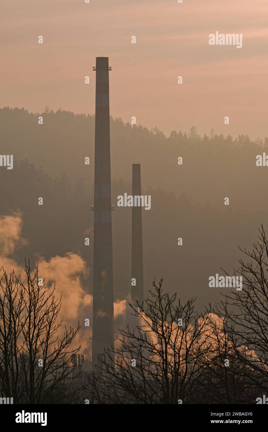 Hoher alter Schornstein im Industriegebiet und nebeliger Sonnenuntergang im Hintergrund. Roznov Pod Radhostem, Tschechische republik. Stockfoto