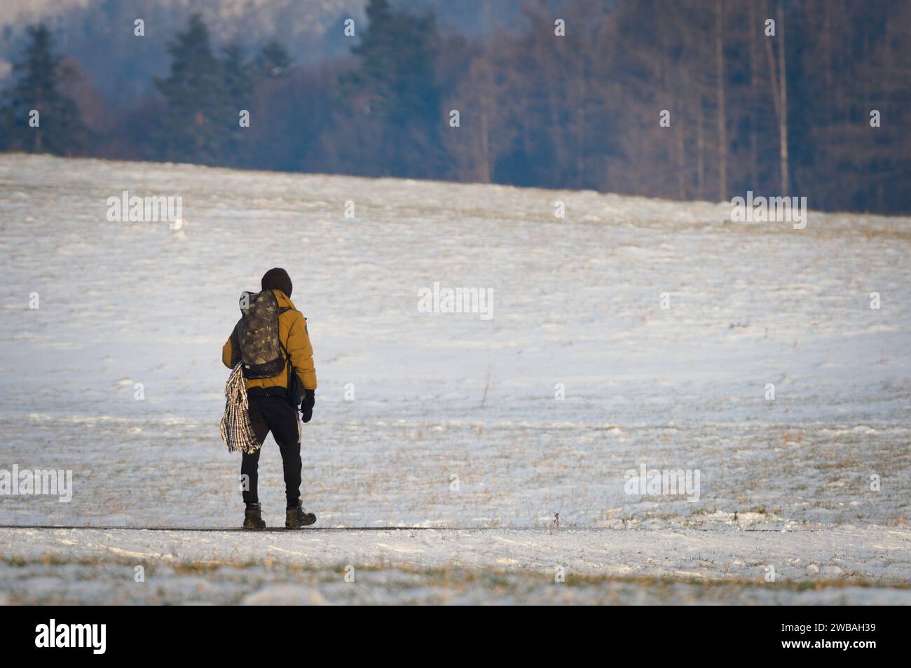 Ein einsamer junger Mann wandert durch die schneebedeckte Landschaft. Winterwandern in der Natur. Kopierbereich. Stockfoto