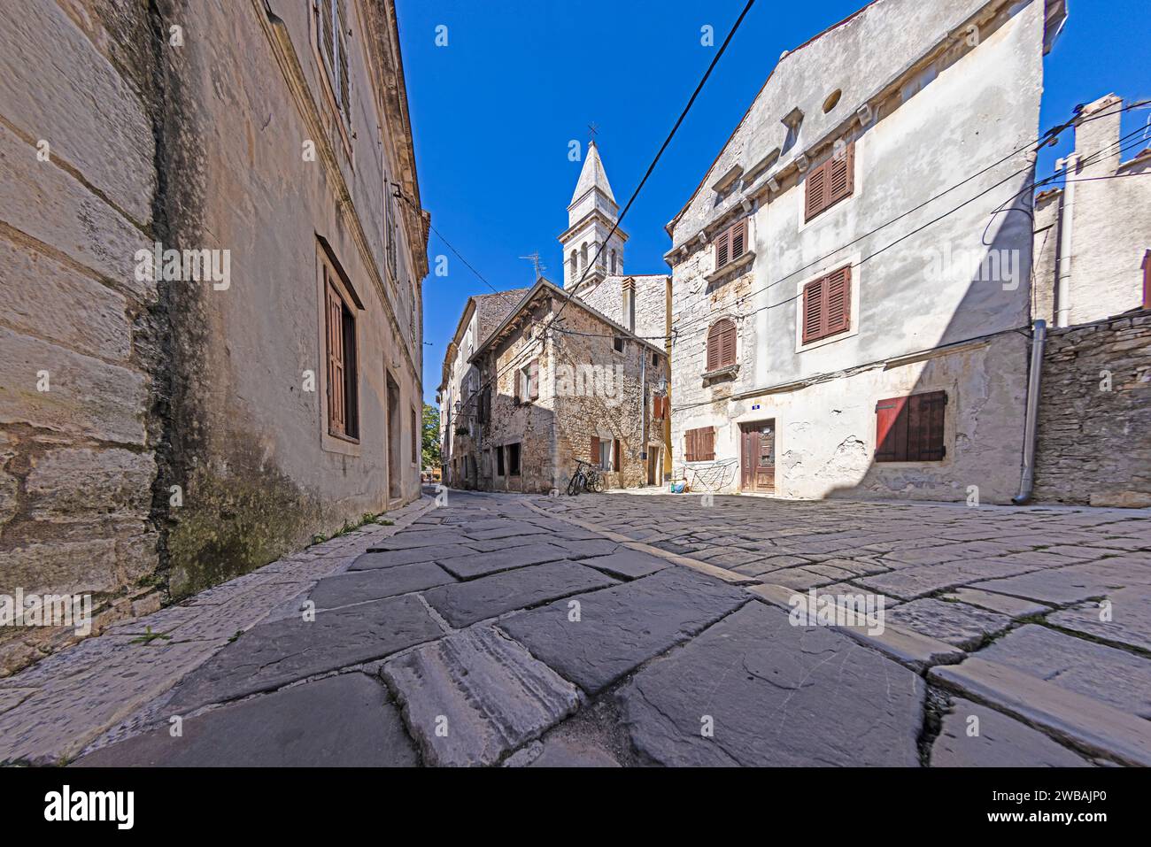 Bild einer typischen Straßenszene aus der historischen kroatischen Stadt Voznjan mit Kopfsteinpflasterstraßen und alten Gebäuden im Morgenlicht Stockfoto