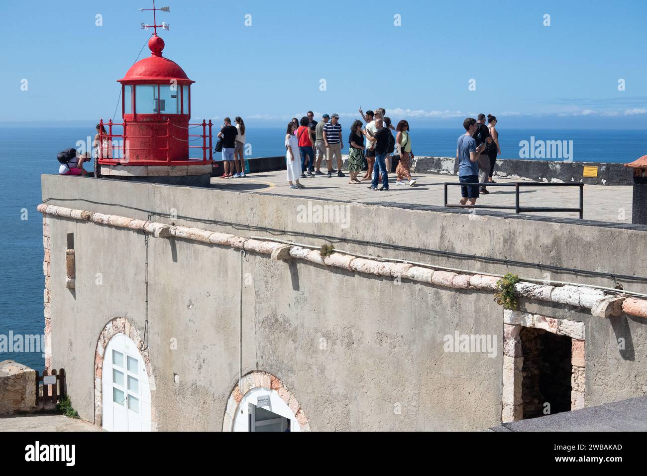 Besucher besuchen den roten Leuchtturm im Fort und das wissenschaftliche Meeresmuseum am Big Wave-Standort Nazare Portugal Stockfoto