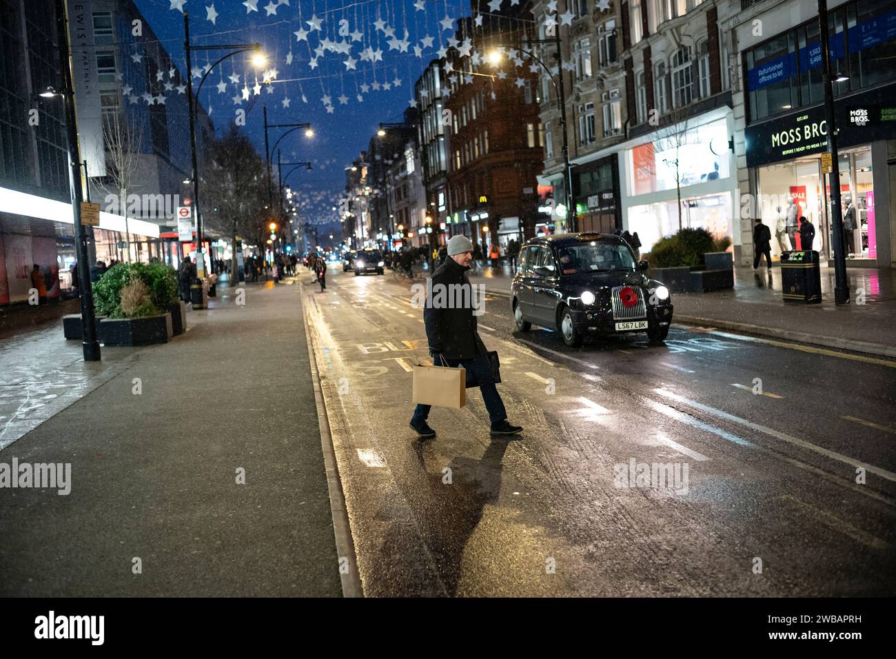 Käufer trotzen dem kalten Winter bei eisigen Schneeregen und Regenschauern auf der Oxford Street, Londons geschäftigster High Street, England, Großbritannien Stockfoto