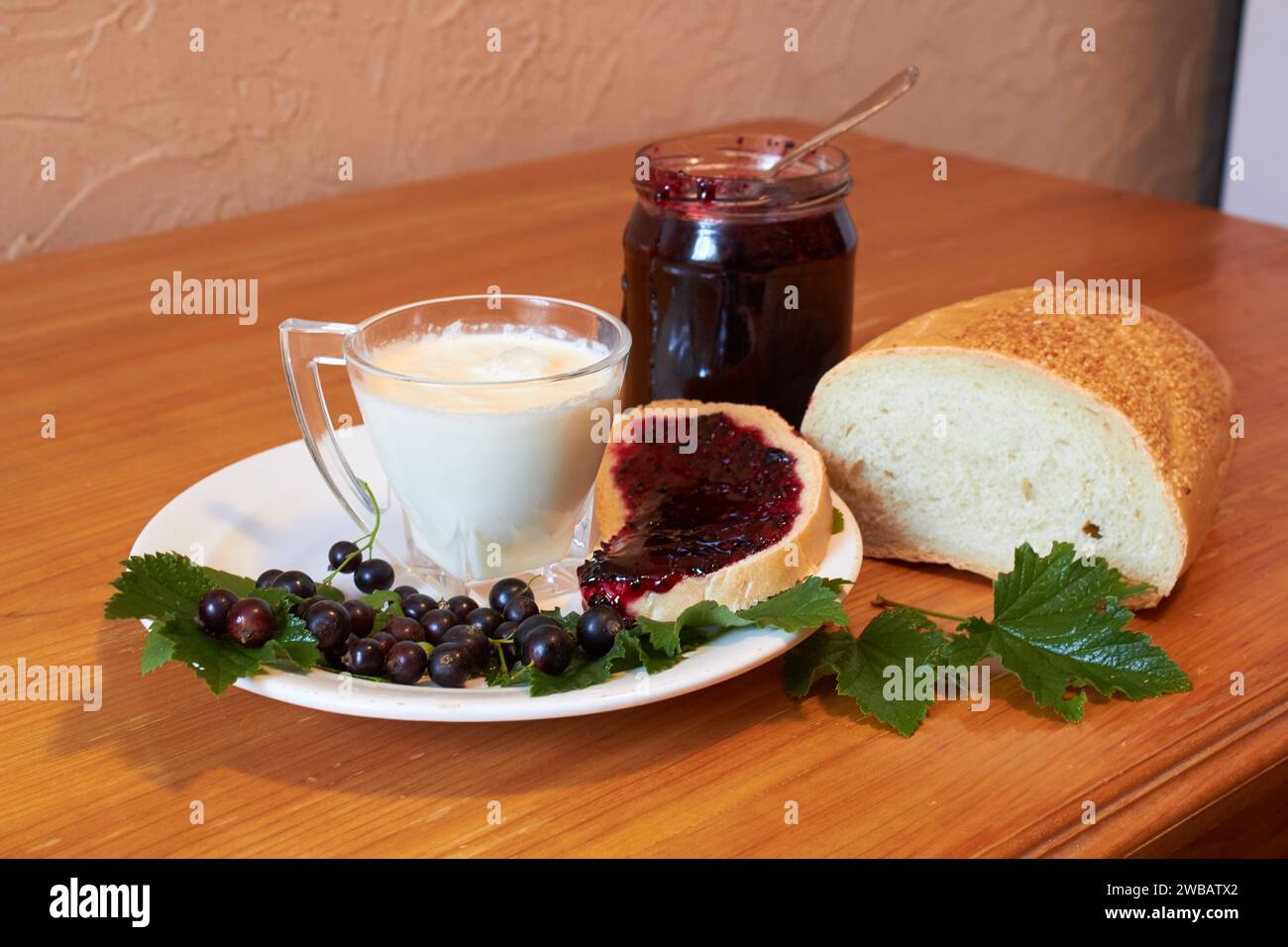 Milch mit Brot und Marmelade mit Johannisbeere auf dem Tisch Stockfoto