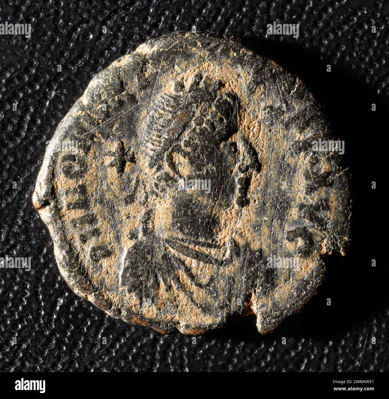 Kaiser Honorius Porträt auf altrömischer Münze, altes beschädigtes Metallgeld isoliert auf schwarzem Hintergrund. Thema der klassischen Kupfer- oder Bronzestruktur, Rom Stockfoto