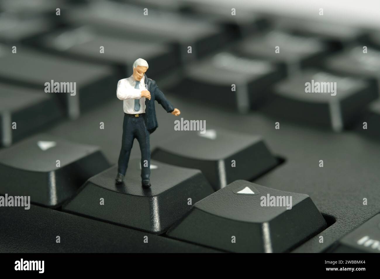 Miniatur-Kleinkinder-Spielfiguren-Fotografie. Ein Geschäftsmann, der sich mit Anzug über der Tastatur vorbereitet. Isoliert auf weißem Hintergrund. Bild-ph Stockfoto